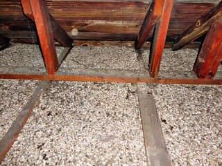 Chevrons bruns et isolation dans un grenier ; des poutres en bois soutiennent la structure du toit.