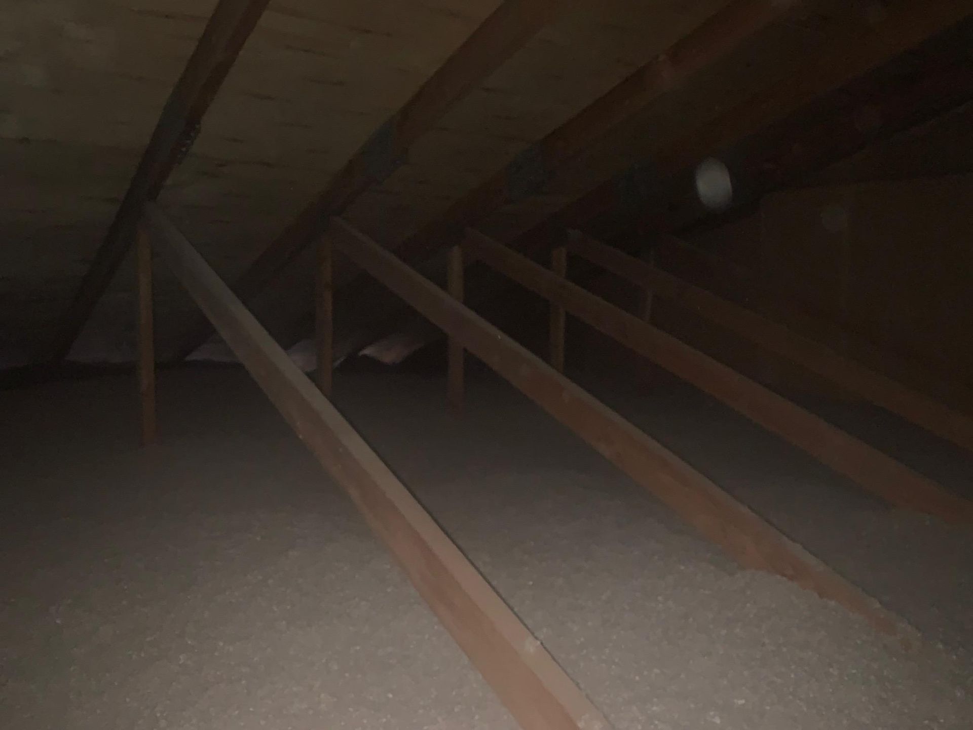 Vue de l'intérieur d'un grenier avec poutres en bois et isolation.