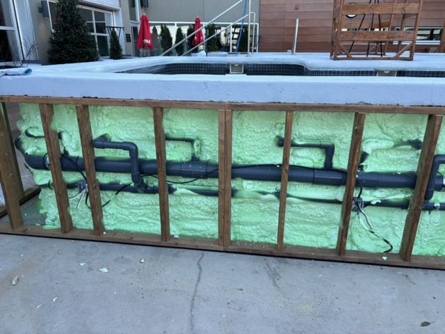 Construction de la piscine : structure en bois avec tuyaux et isolation. Mousse verte pour le remplissage des espaces.