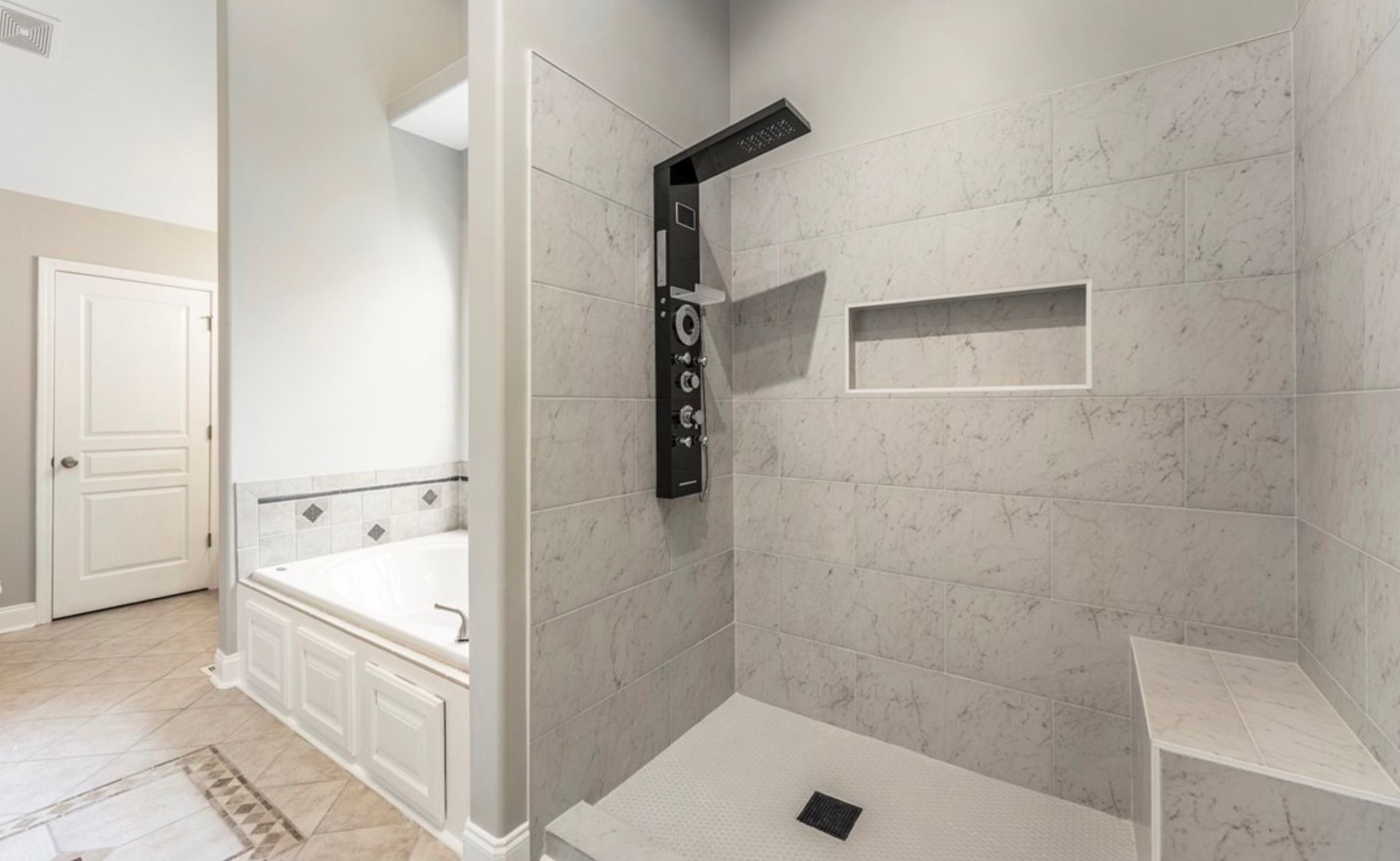 Modern bathroom with walk-in tiled shower, black fixtures, and adjacent white bathtub