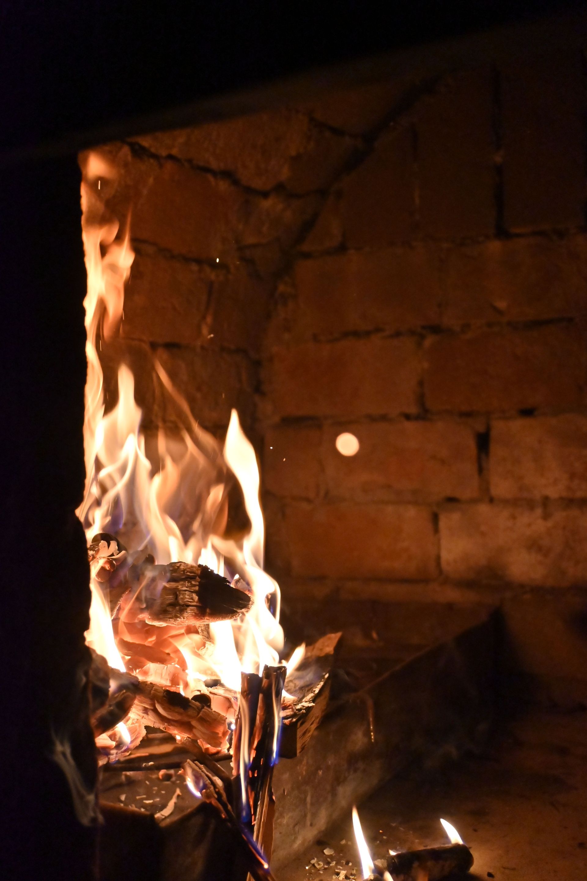 Paper burning in a brick fireplace, with tall orange flames and glowing embers.