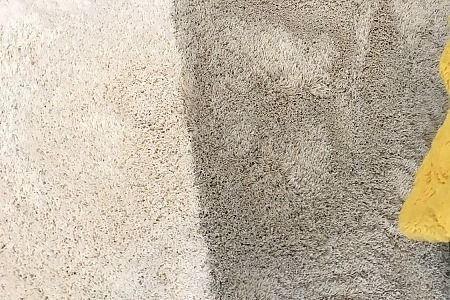 Close-up of two-tone beige and gray carpet with a yellow cloth at the right edge