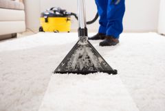 Carpet cleaning with a vacuum wand in a bright living room