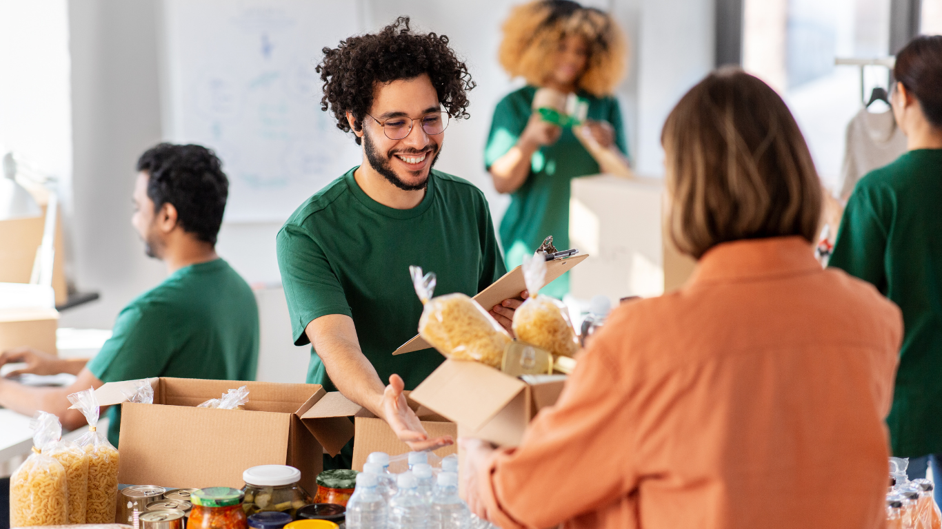 Volunteers in green shirts packing and distributing food donations in boxes.