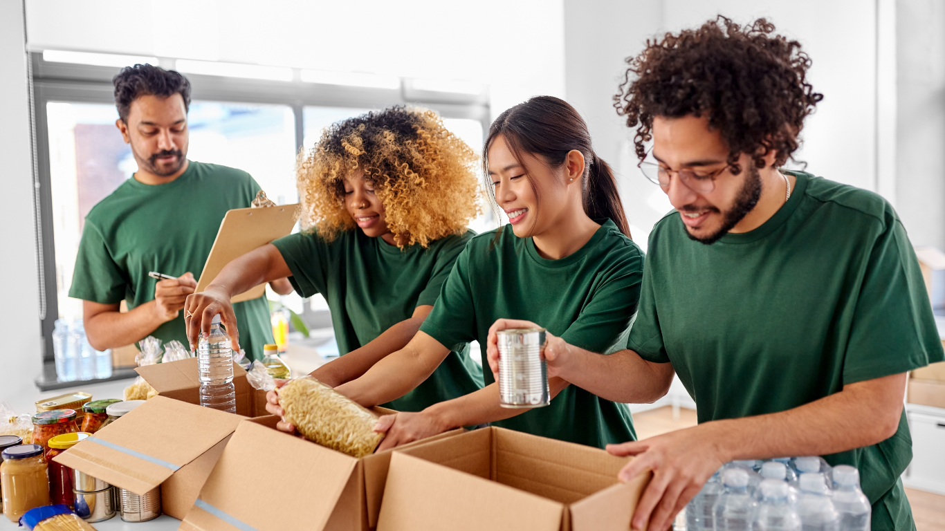 Volunteers in green shirts packing food into boxes at a food bank.