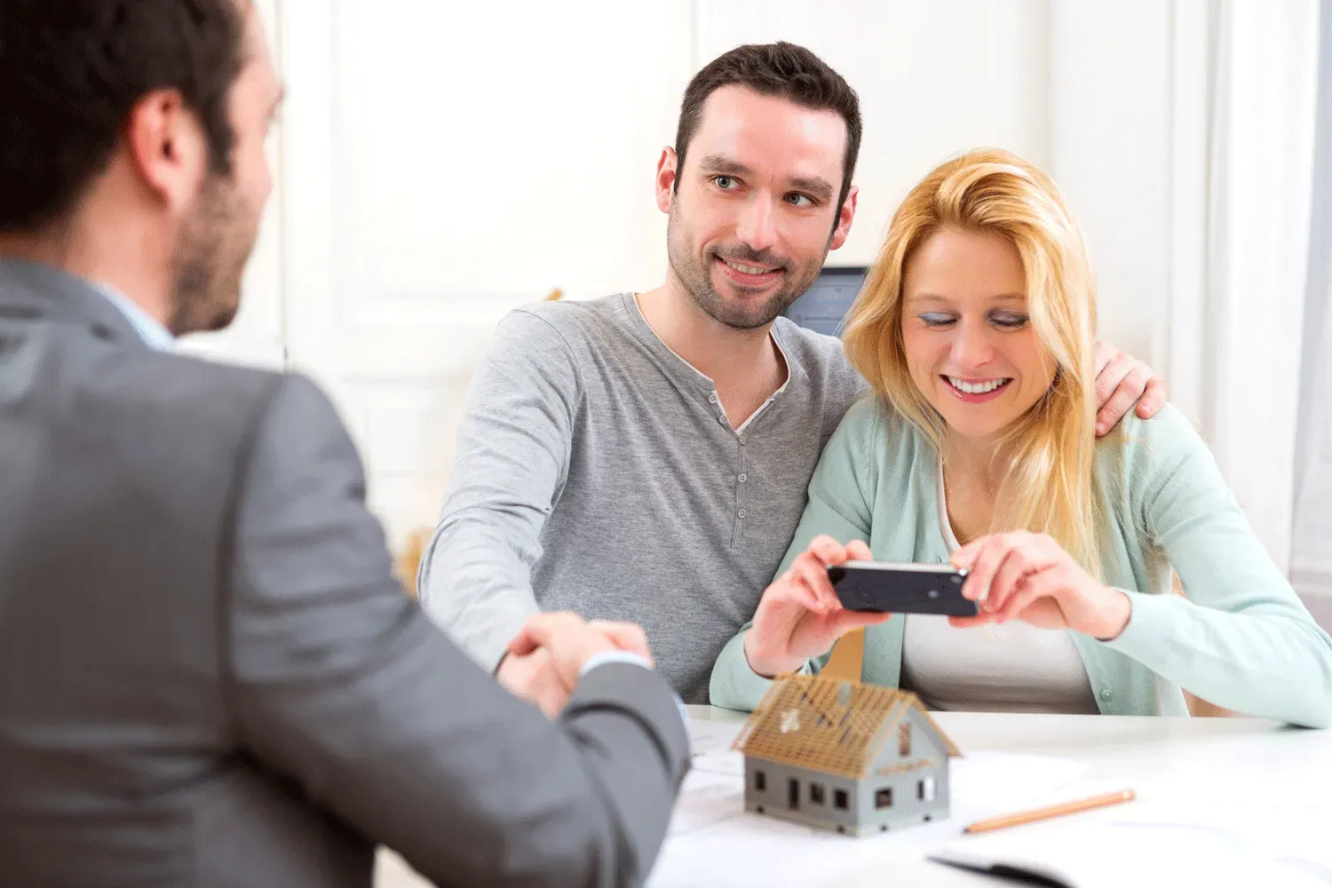 A man and woman are sitting at a table looking at a cell phone.