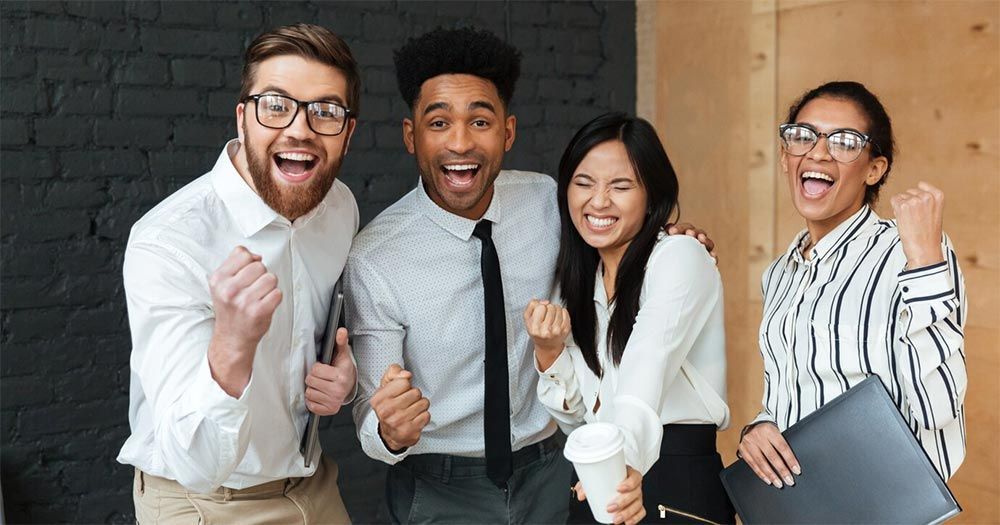 A group of business people are standing next to each other in an office.