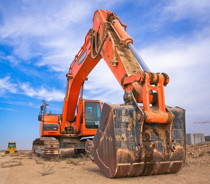 A large orange excavator is sitting in the dirt on a construction site