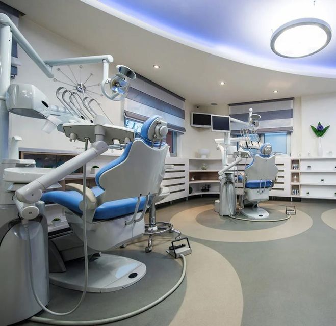 A dental office with blue chairs and white equipment