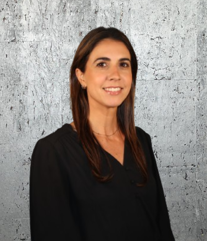 A woman in a black shirt is smiling in front of a gray wall