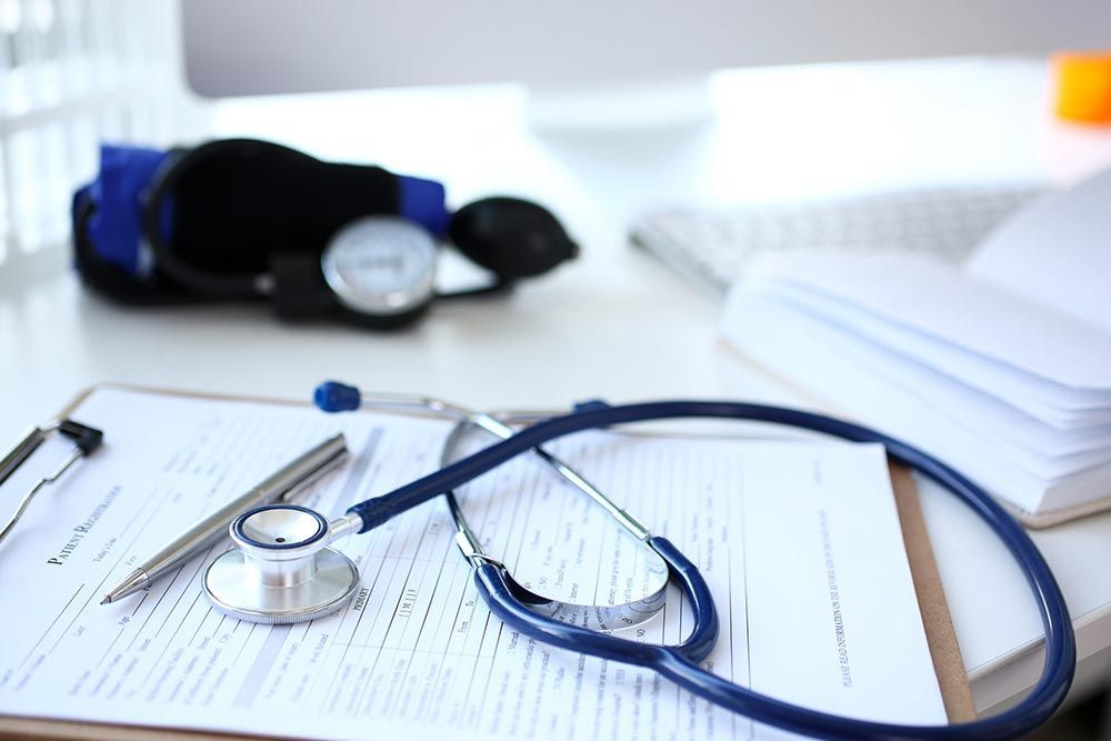 A stethoscope is sitting on top of a clipboard on a table.