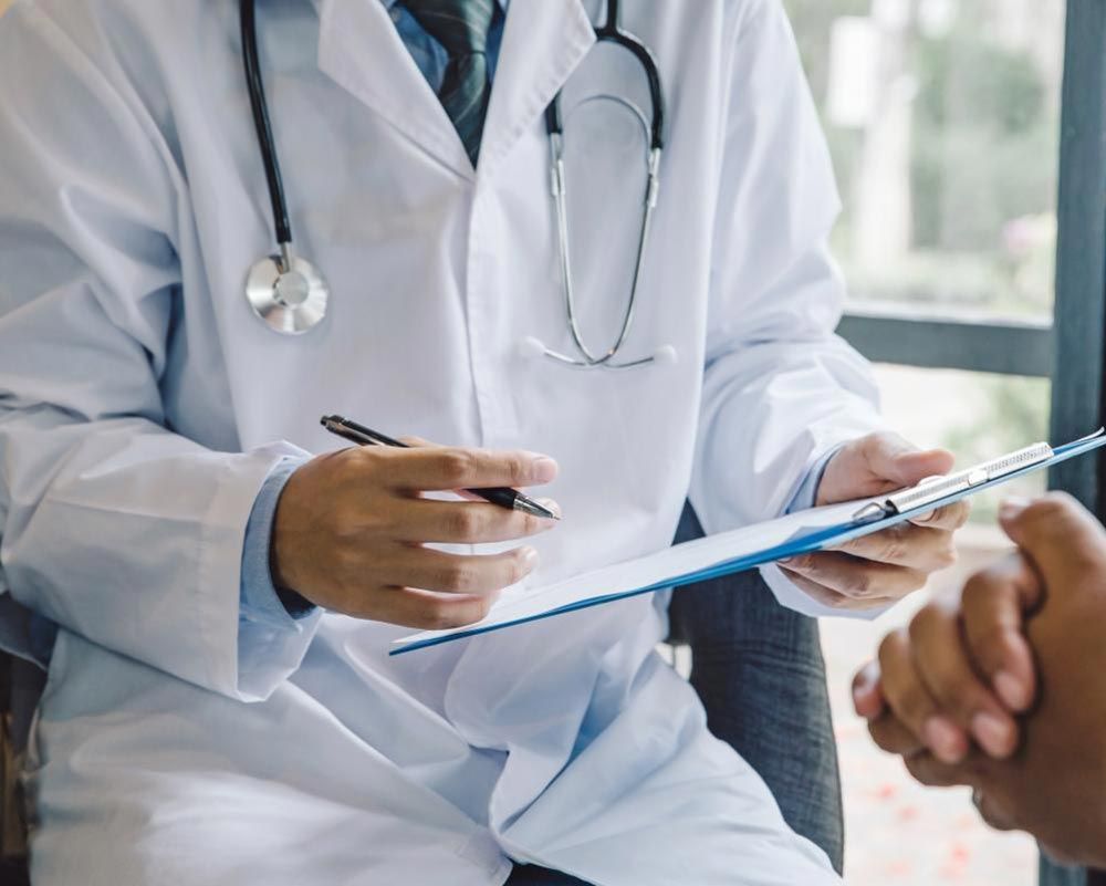 A doctor is holding a clipboard and talking to a patient. - accounting for medical practices