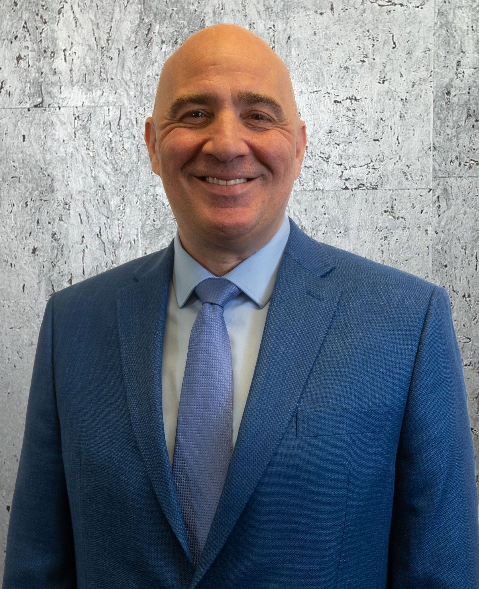 A man in a blue suit and tie is smiling for the camera.