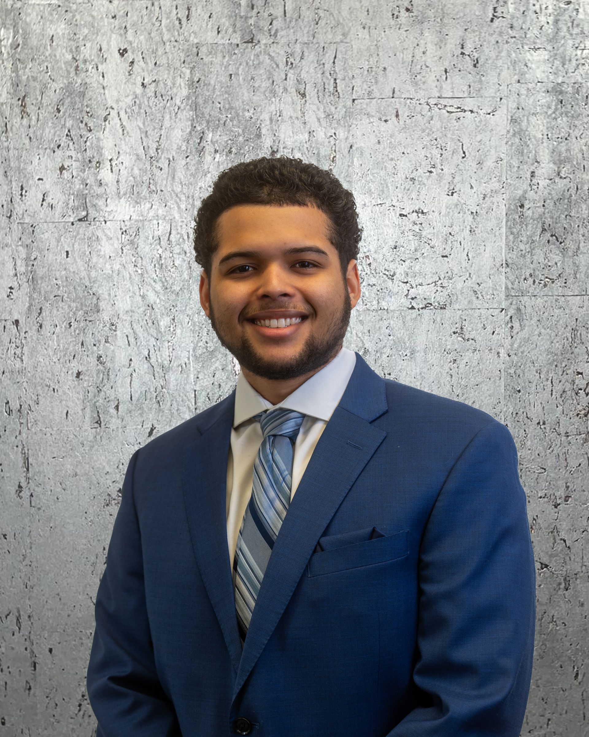 A man in a blue suit and tie is smiling for the camera.