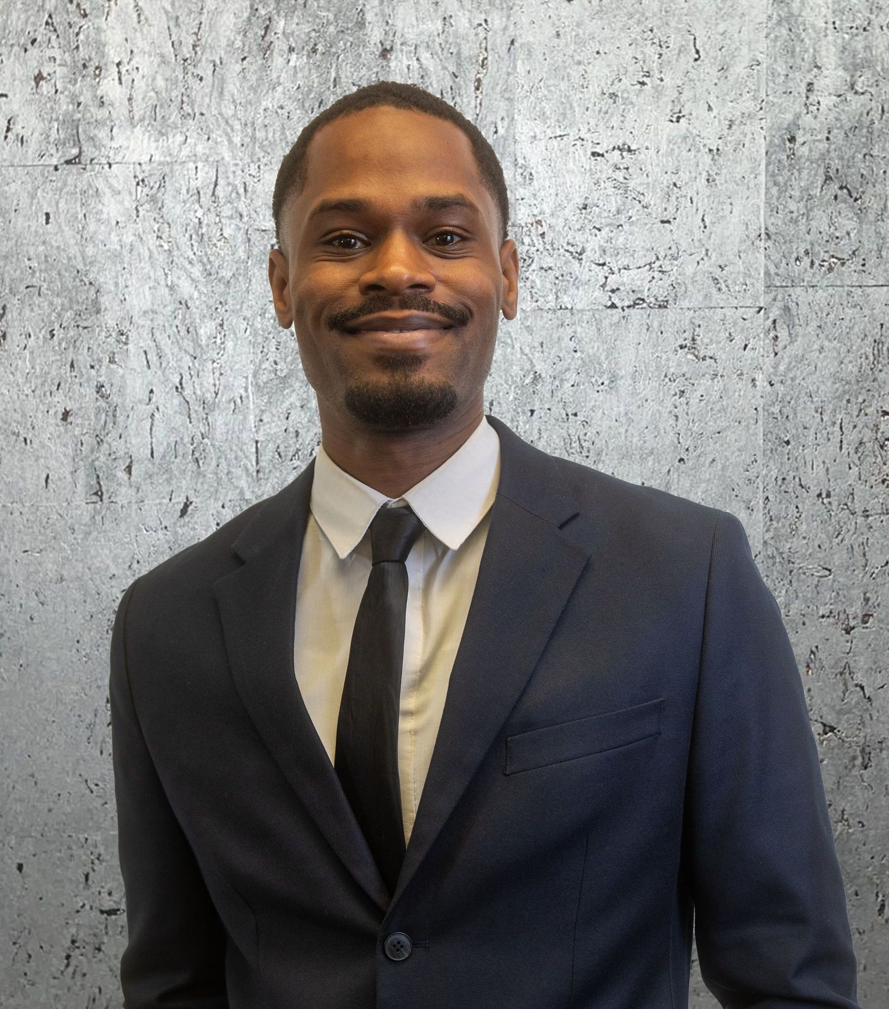 A man in a suit and tie is smiling for the camera.