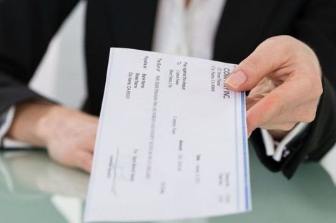 A person in a suit is holding a check in their hand.