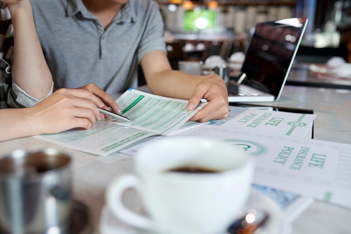 Two people are sitting at a table looking at a menu.