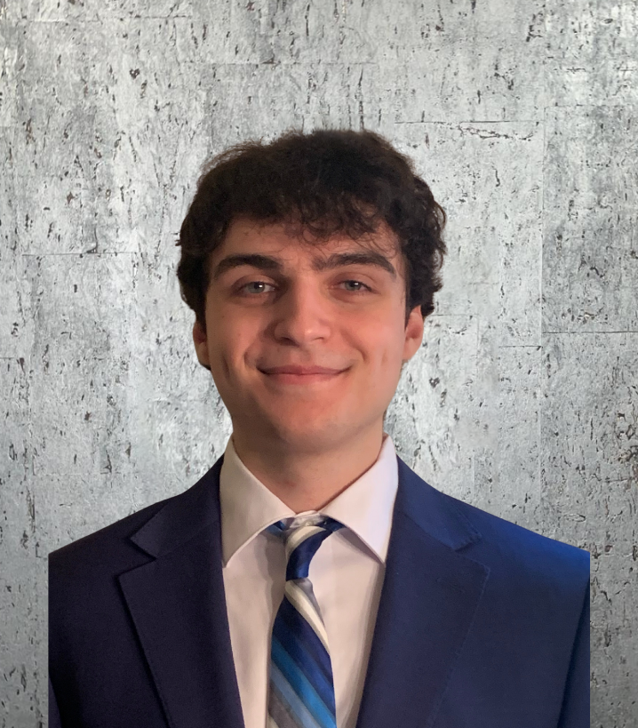 A young man in a suit and tie smiles for the camera