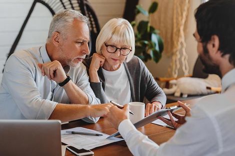 An older couple is sitting at a table talking to a man.