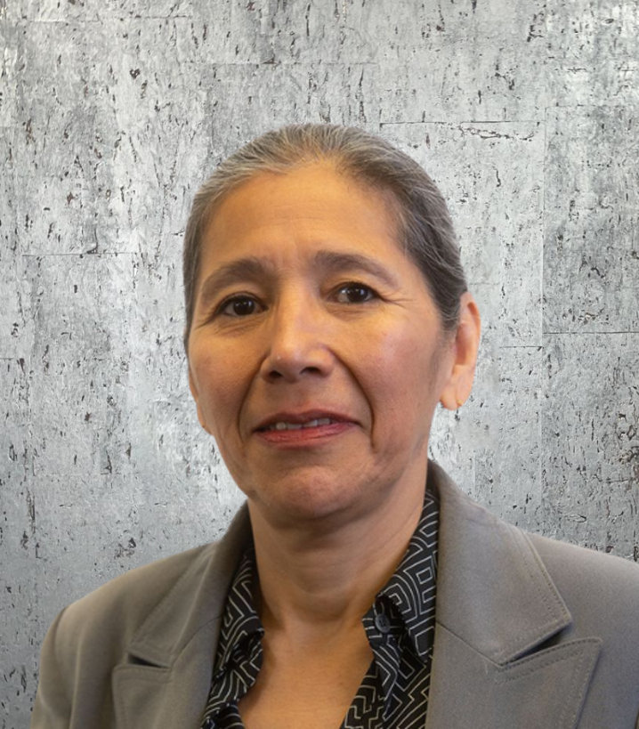 A woman wearing a grey jacket and a black shirt smiles for the camera