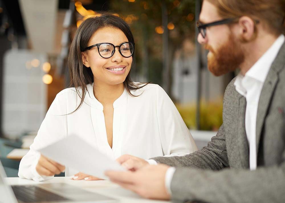 A man and a woman are sitting at a table looking at a piece of paper.