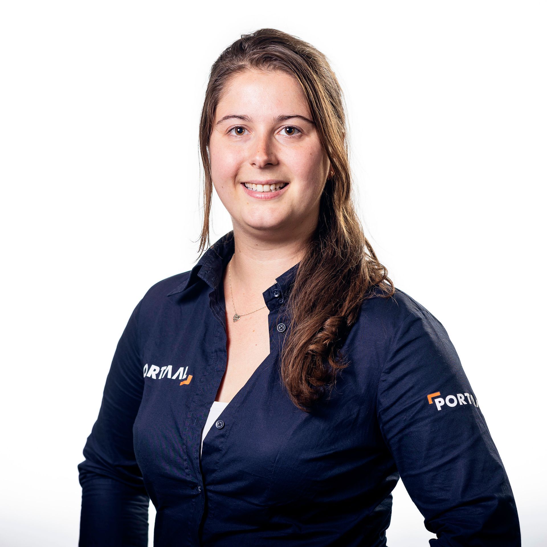 Een vrouw in een donkerblauwe blouse met kraag glimlacht en leunt lichtjes naar de camera.
