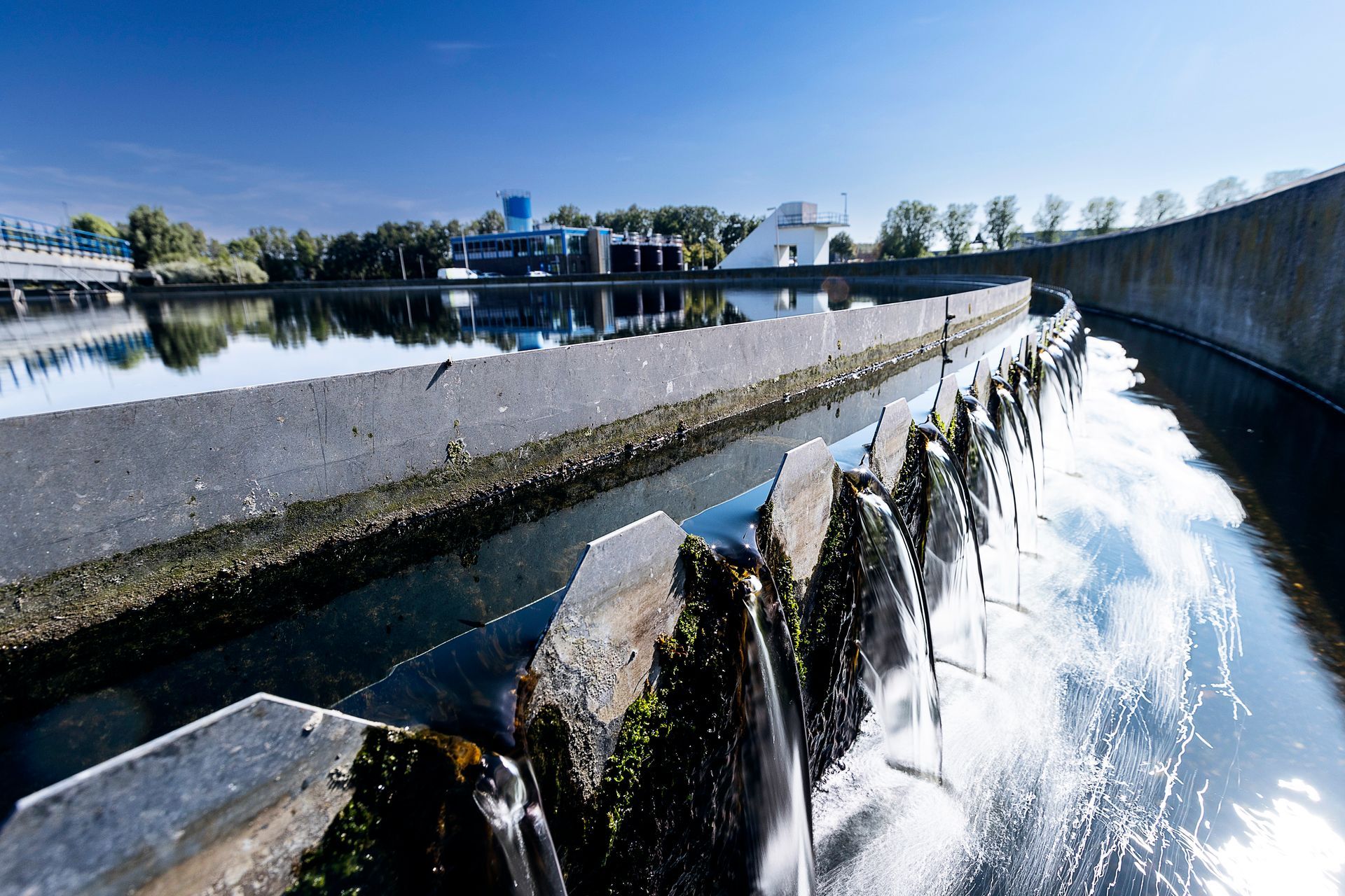 Waterzuiveringsinstallatie met stromend  reflecterend water, blauwe lucht.