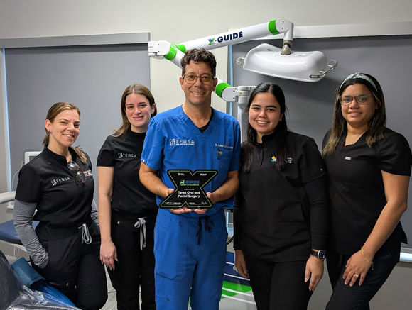An X-shaped X-Guide Center of Excellence award plaque presented to Tersa Oral and Facial Surgery, with signatures below.