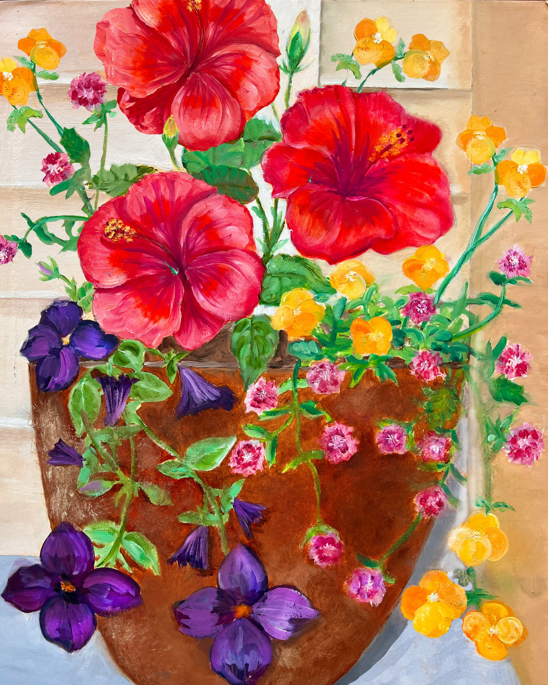 A terracotta pot overflowing with red hibiscus, purple petunias, and yellow pansies against a brick wall.