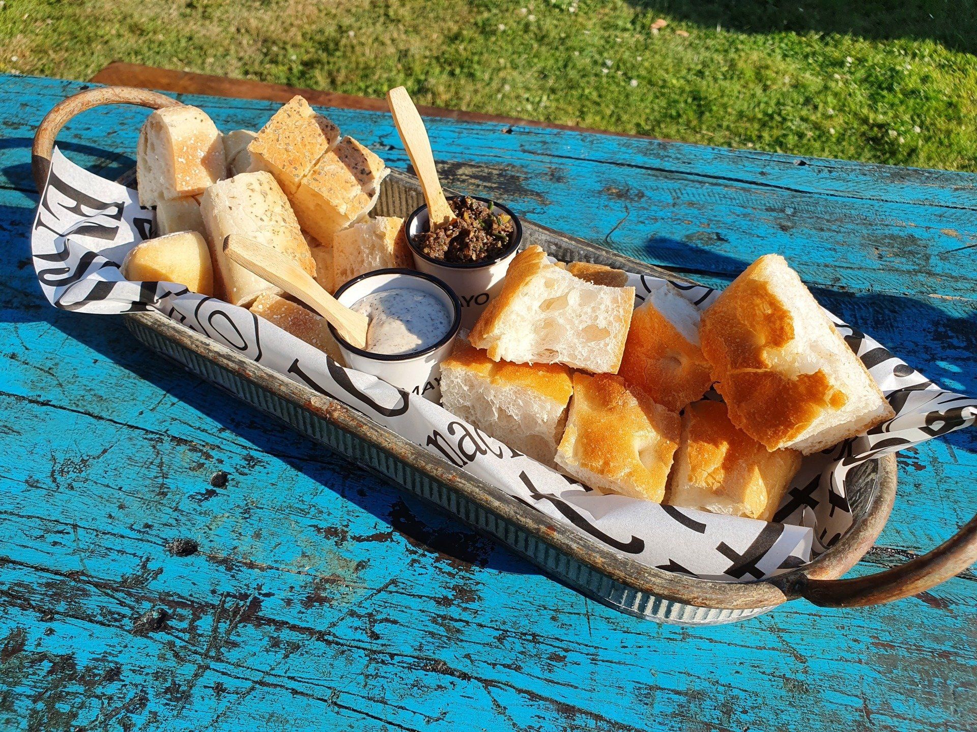Turks brood en dipsauzen worden op een dienblad geserveerd, buiten op een blauwe houten tafel.