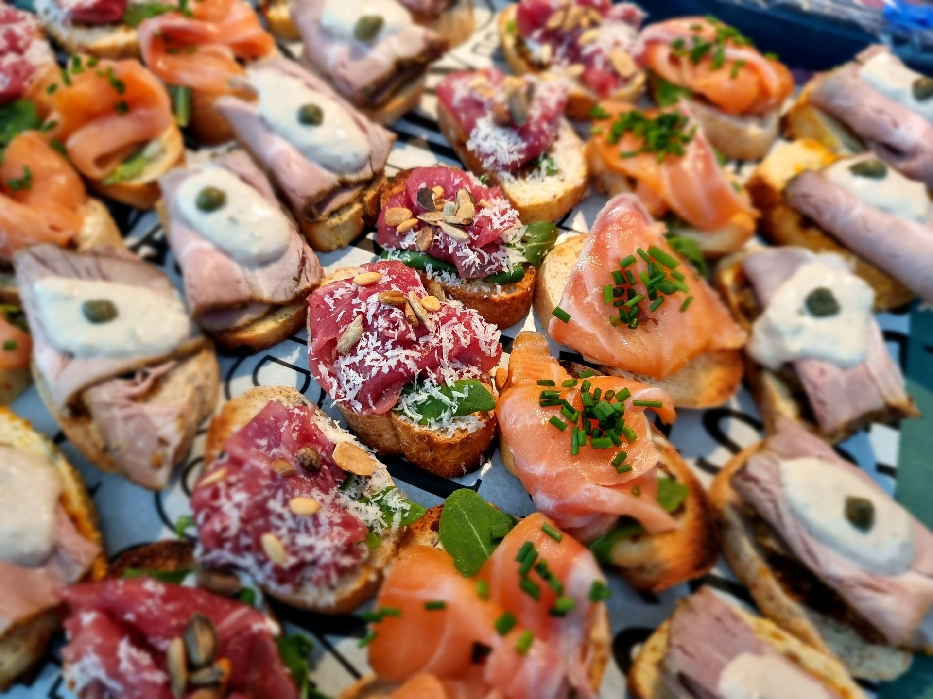 Een assortiment gastronomische hapjes op een schaal, met diverse toppings zoals vlees, vis en kruiden.