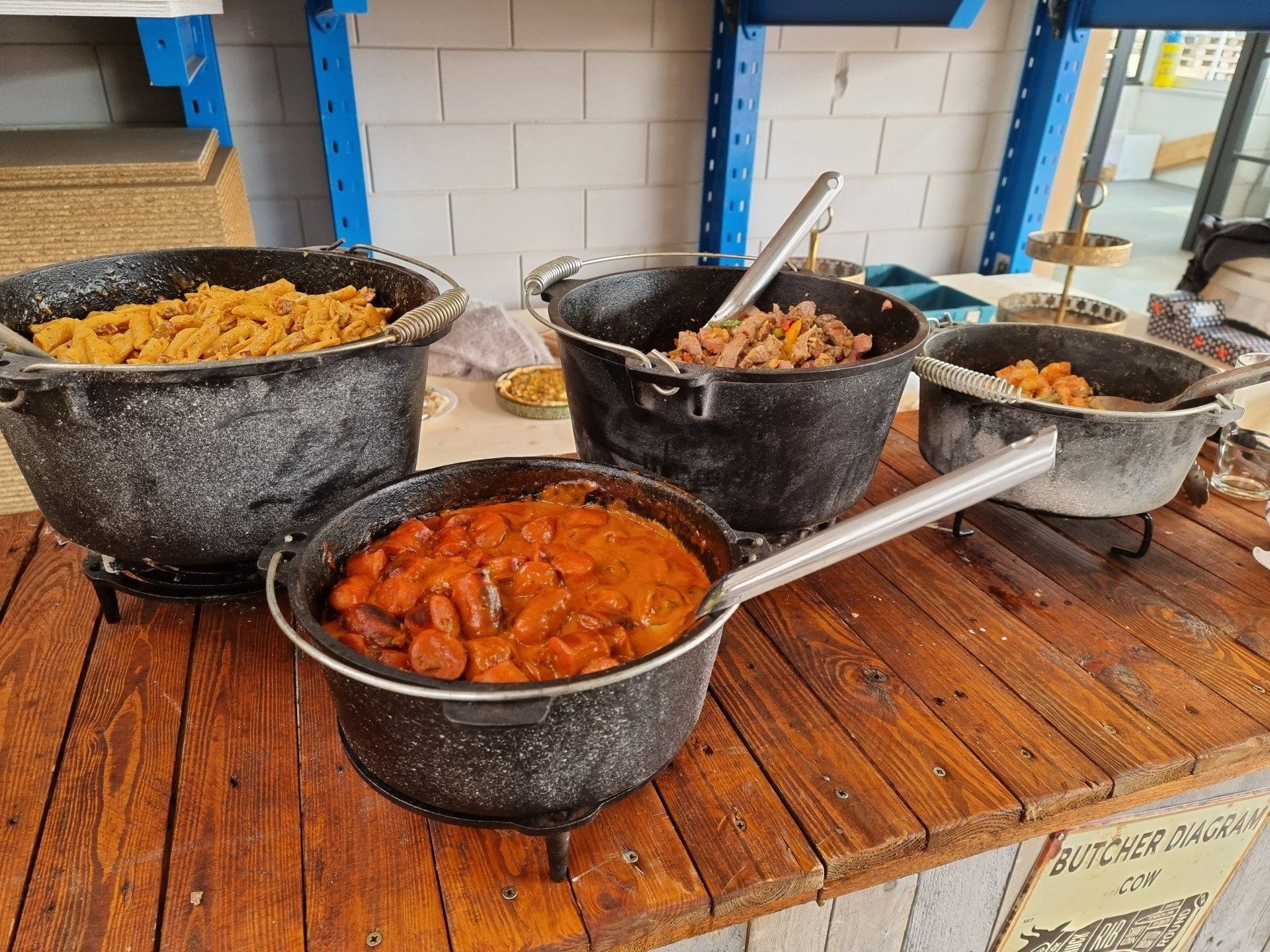 Diverse gerechten in zwarte gietijzeren potten op een houten tafel.