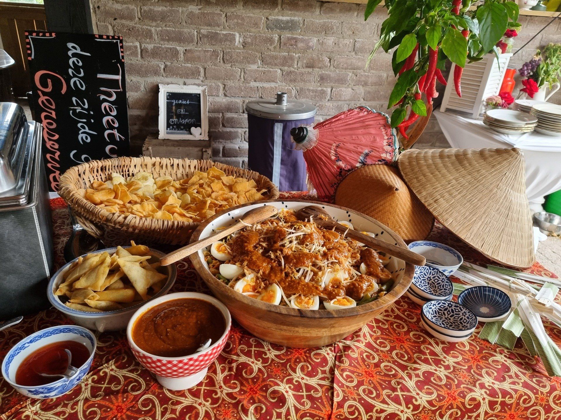 Een buffet met een grote schaal salade, sauzen en snacks op een tafel.