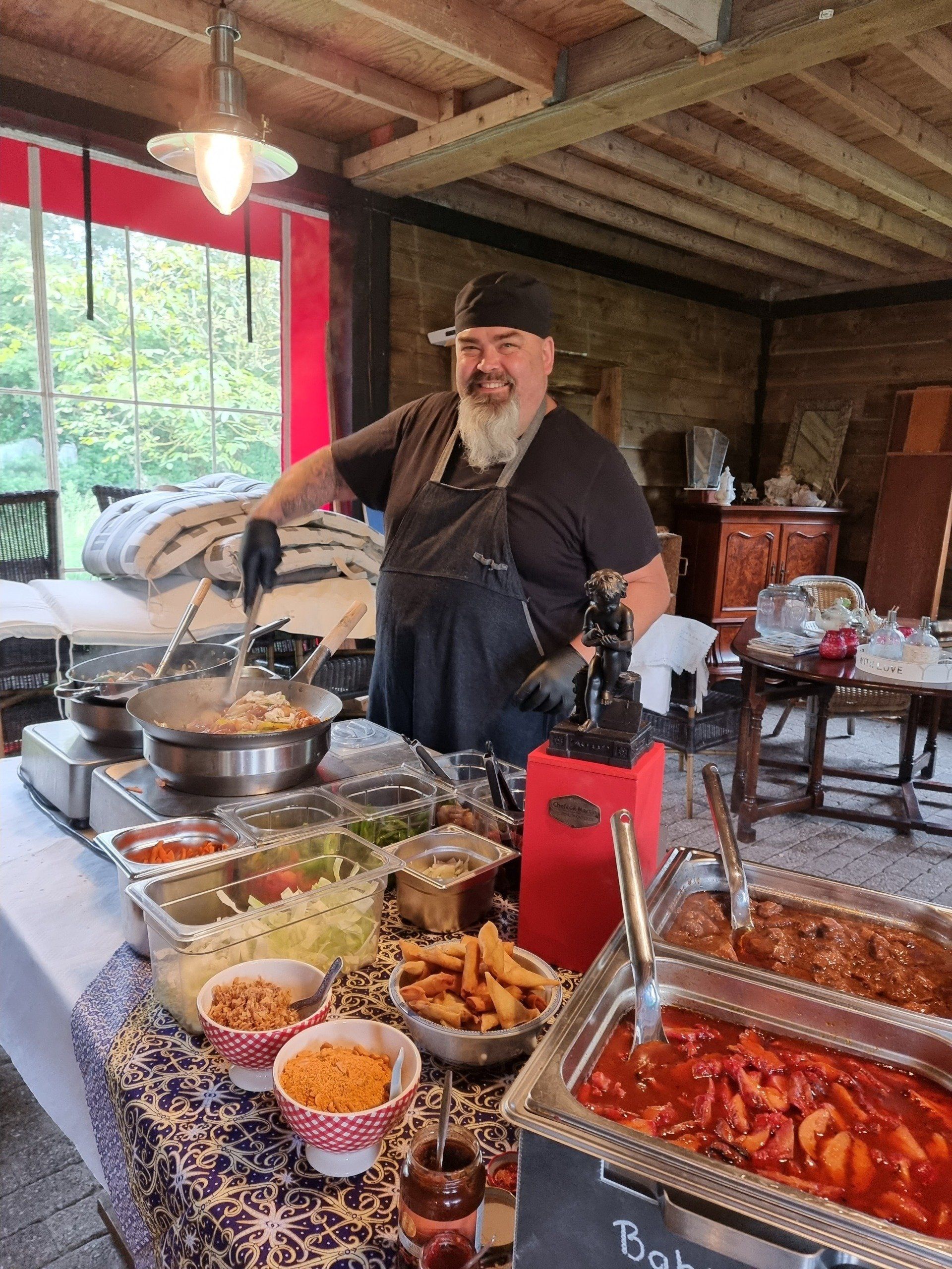 Chefkok Martin bereidt eten voor een evenement met catering in de buitenlucht.