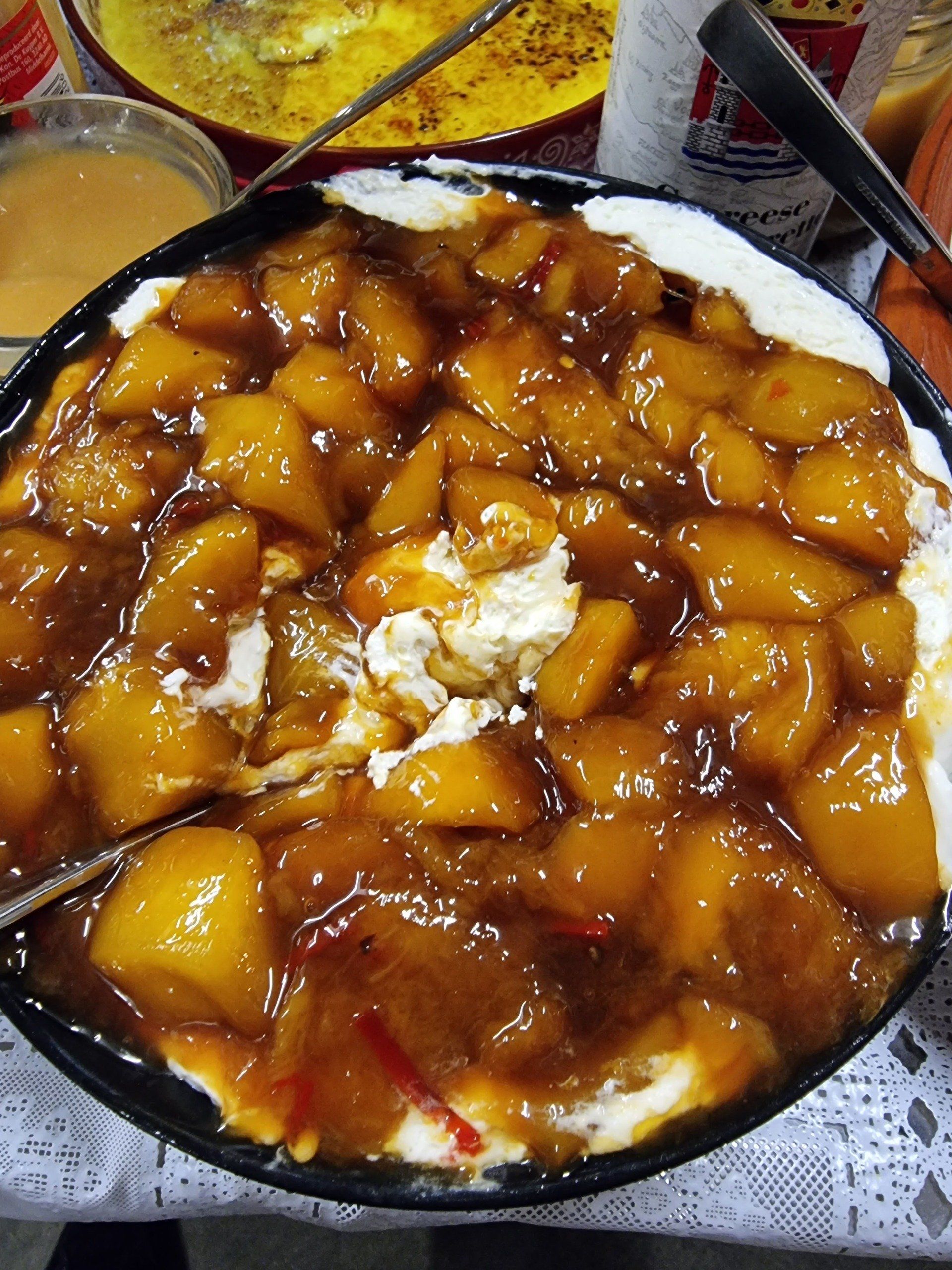 Appel-roomdessert in een donkere kom, met een rijke bruine saus en witte room.