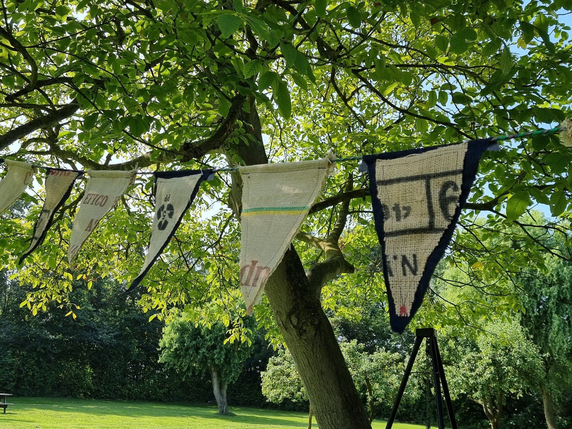 Een slinger van gerecycled jute en jeans hangt aan een boomtak, buiten op een zonnige dag.