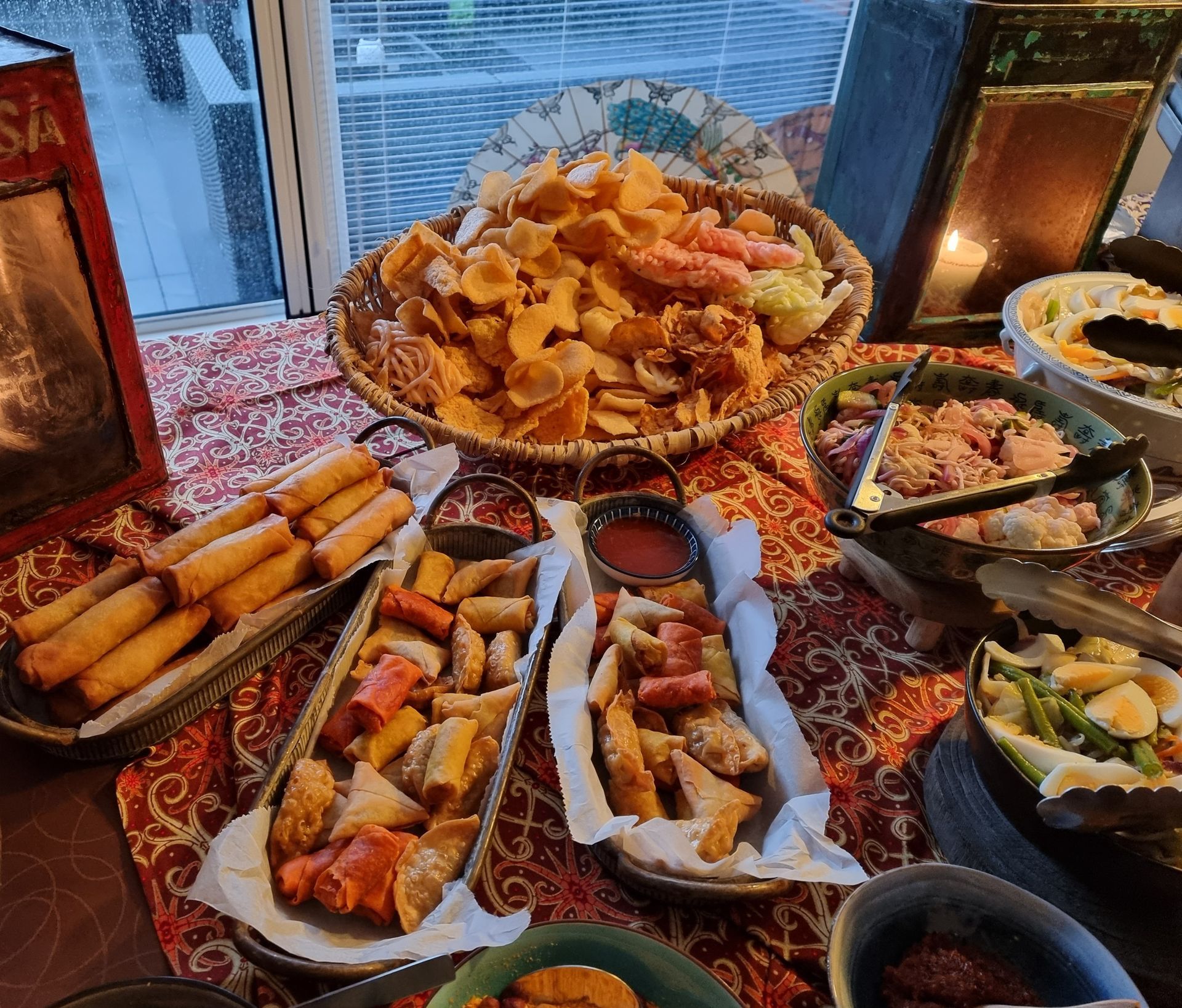 Een buffet met diverse Aziatische gerechten, waaronder loempia's, kroepoek en dumplings.