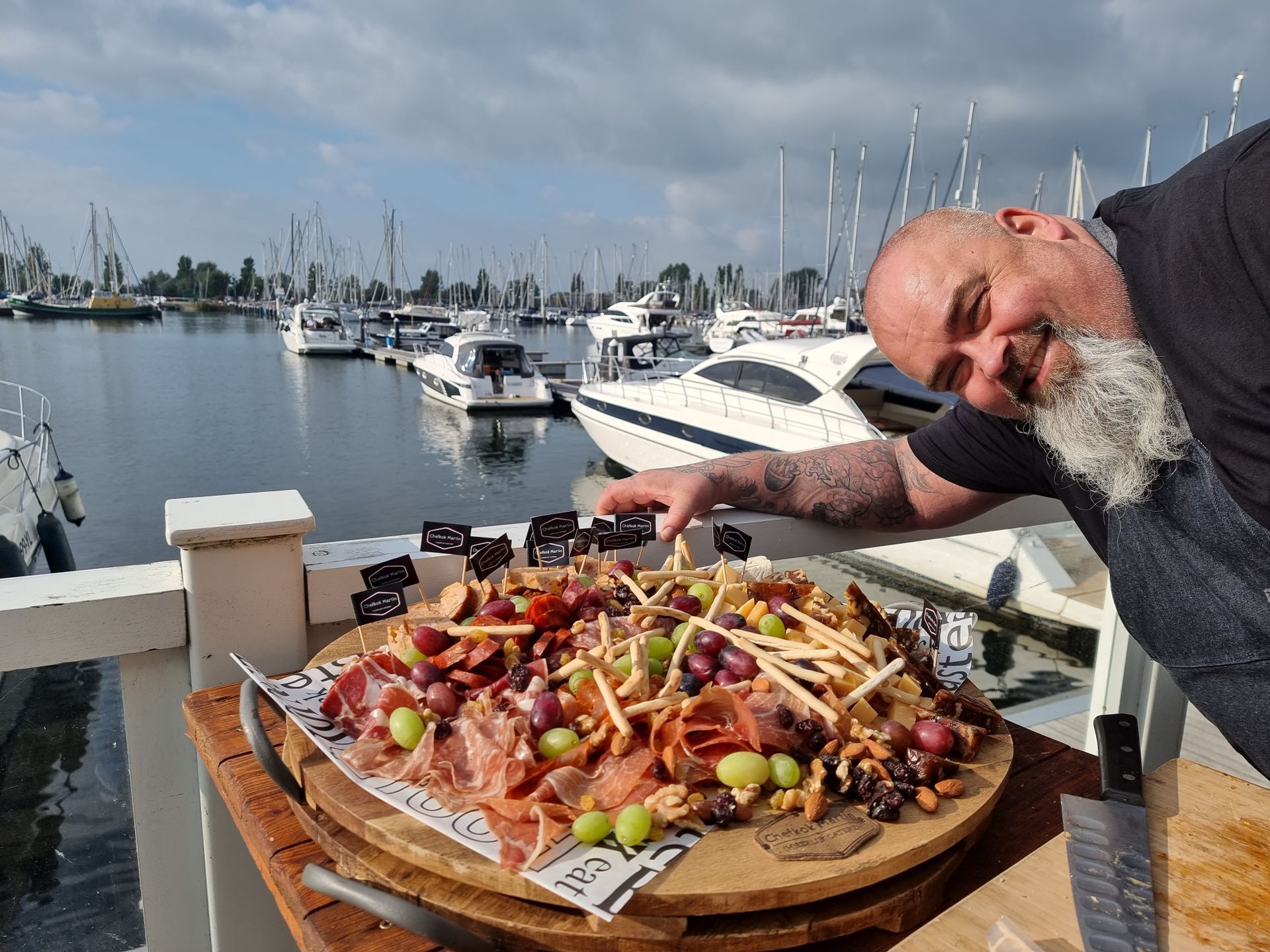 Chefkok Martin wijst naar een charcuterieplank met druiven, kaas en vleeswaren.