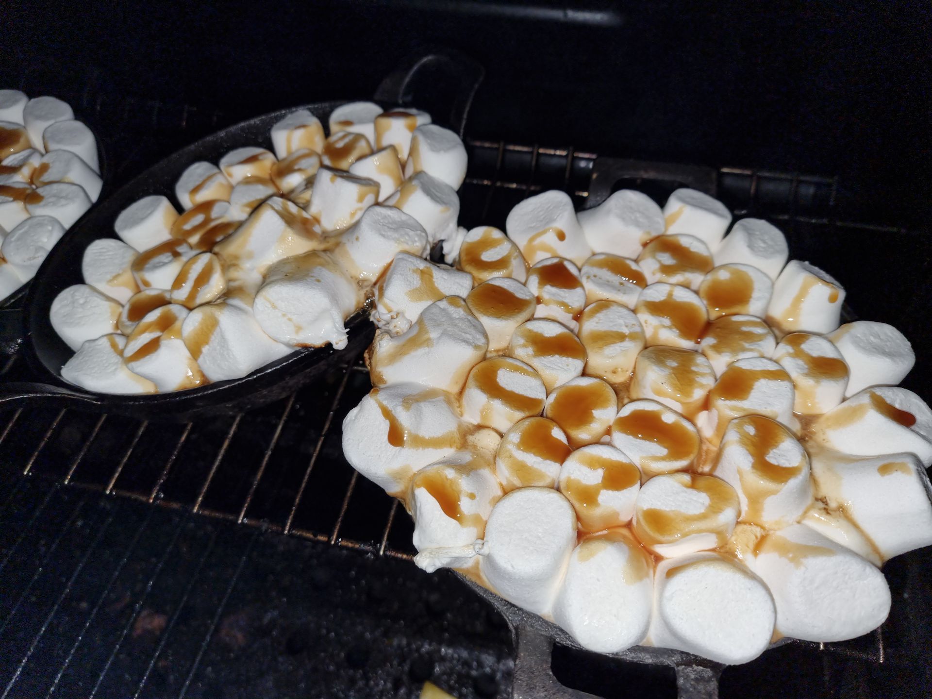 Marshmallows in gietijzeren pannen, besprenkeld met karamel, gegaard in een rookoven.