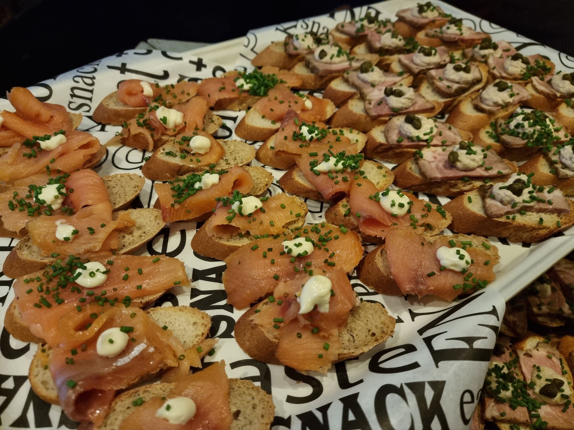 Een schaal met crostini's van gerookte zalm en carpaccio.