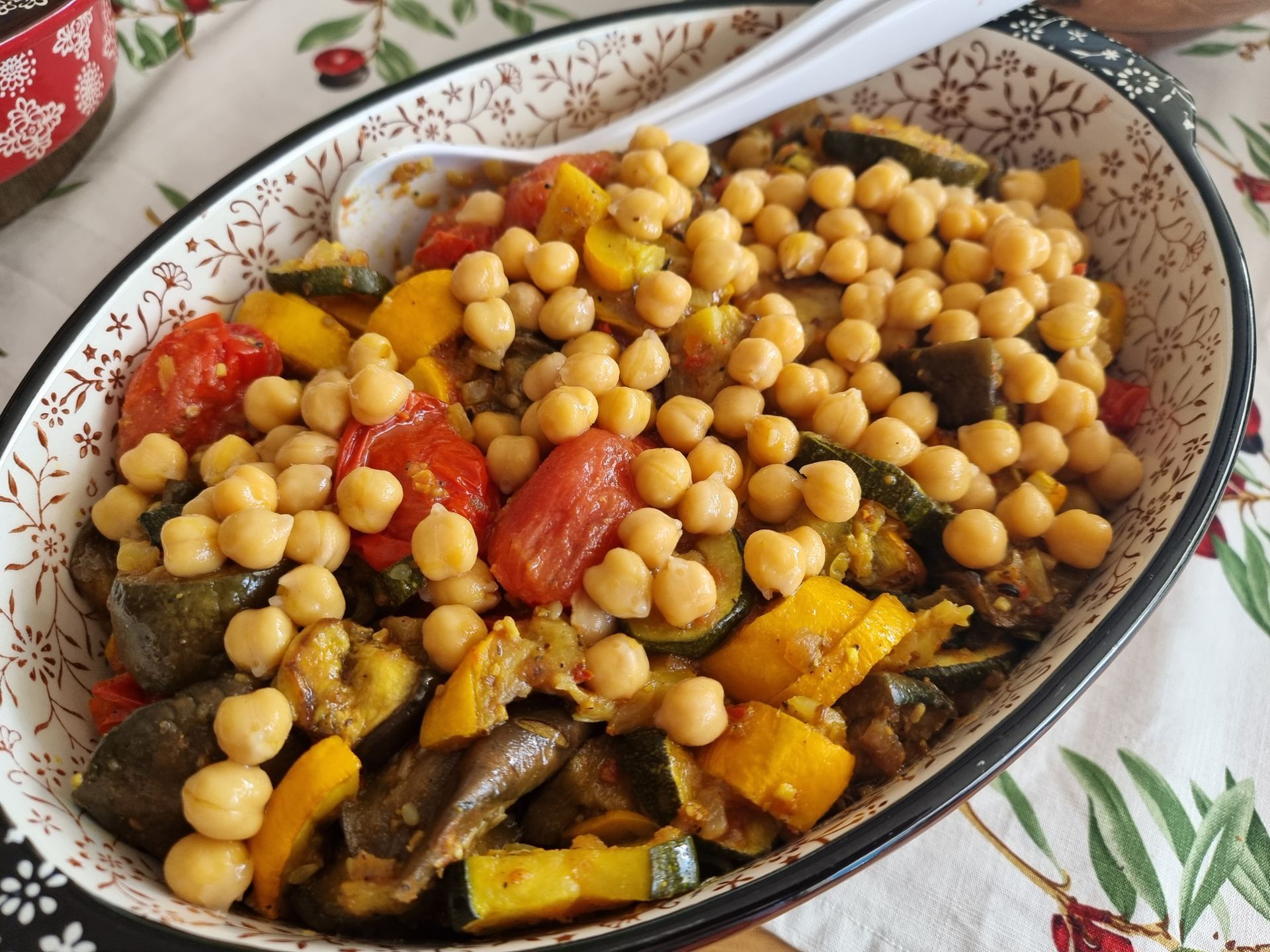 Een kom geroosterde groenten (courgette, tomaten, paprika's) met kikkererwten