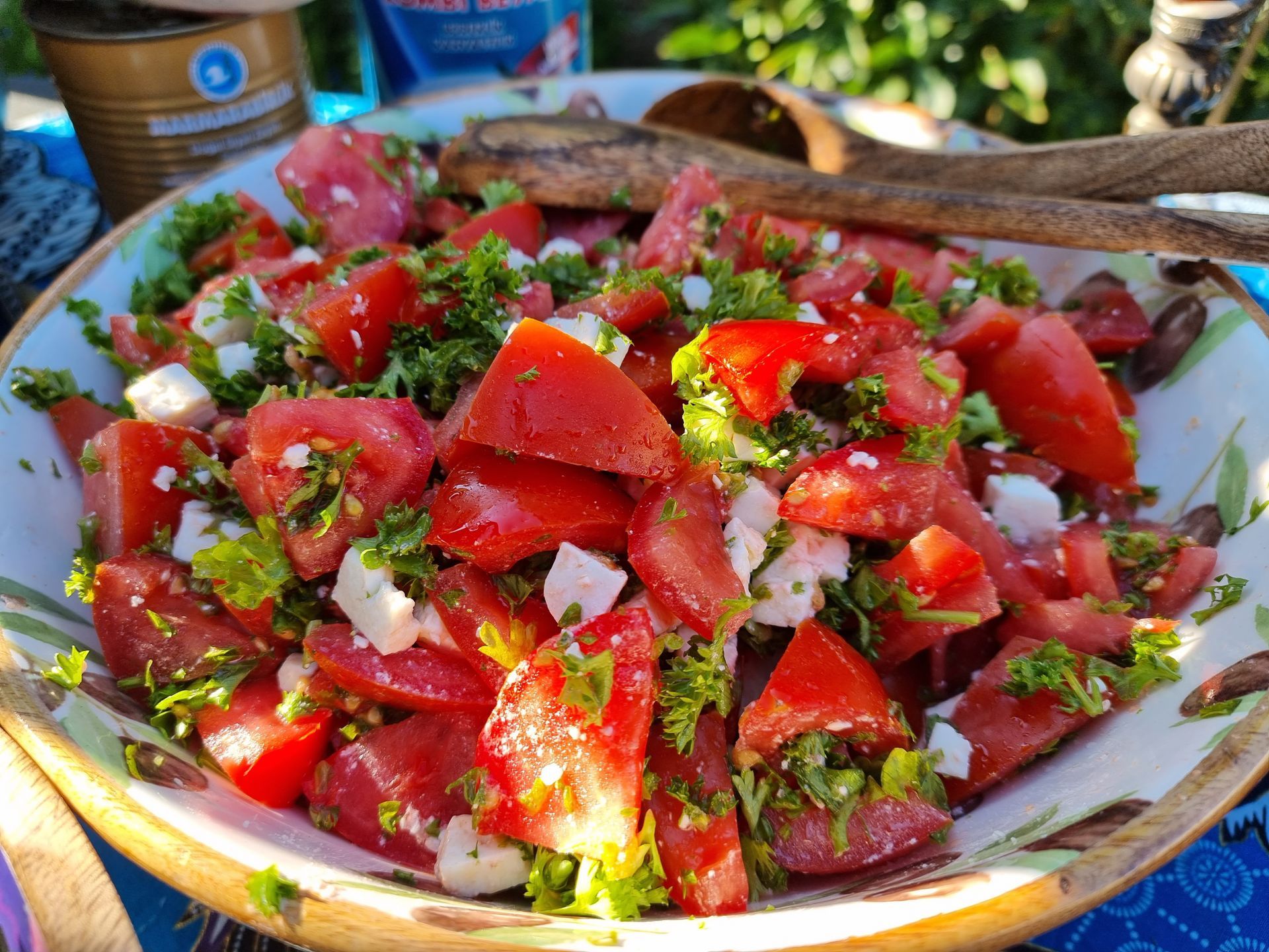Salade van tomaat en feta met verse kruiden in een decoratieve schaal, buiten.