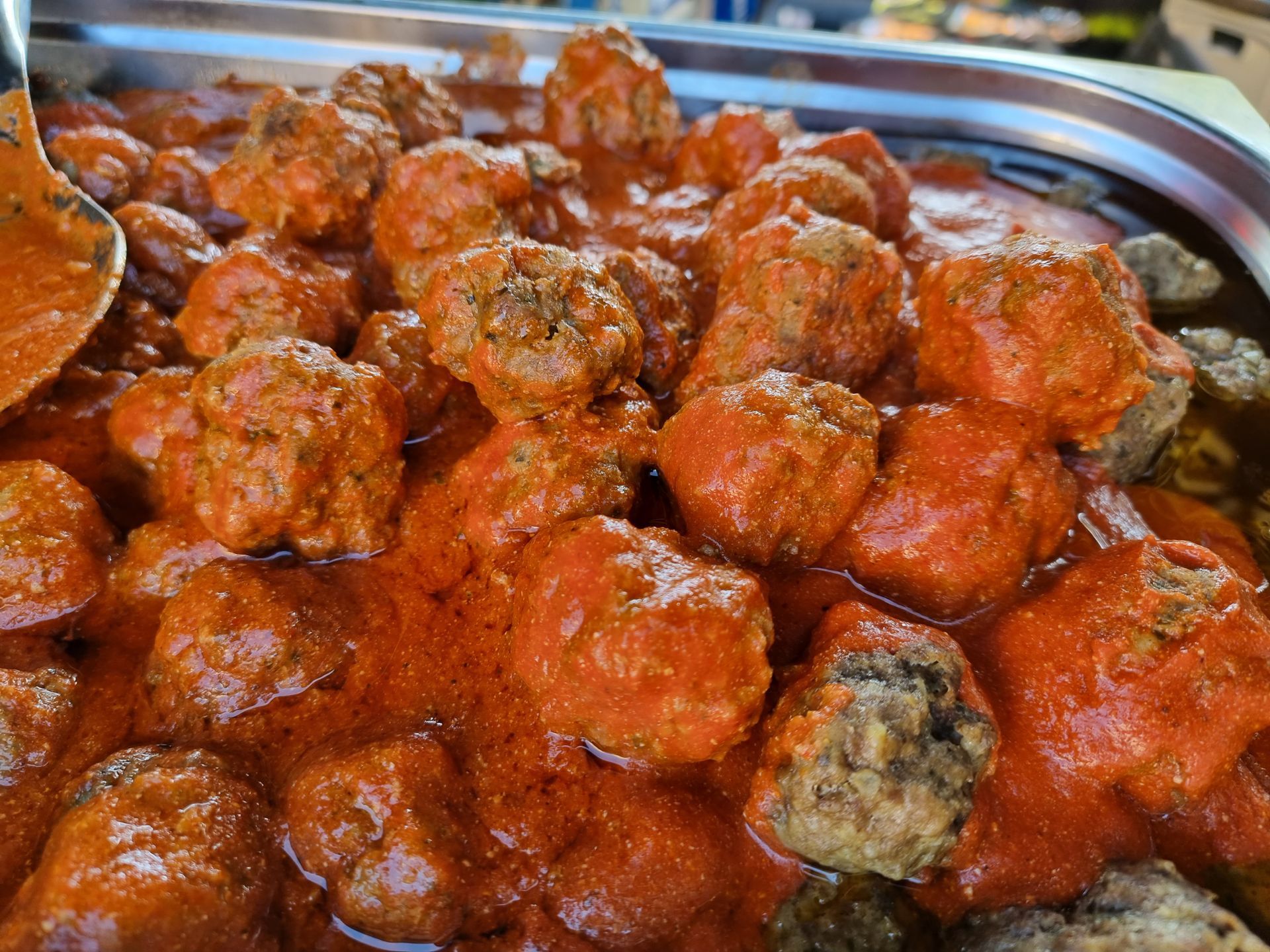 Gehaktballetjes in rode tomatensaus, geserveerd op een metalen schaal.