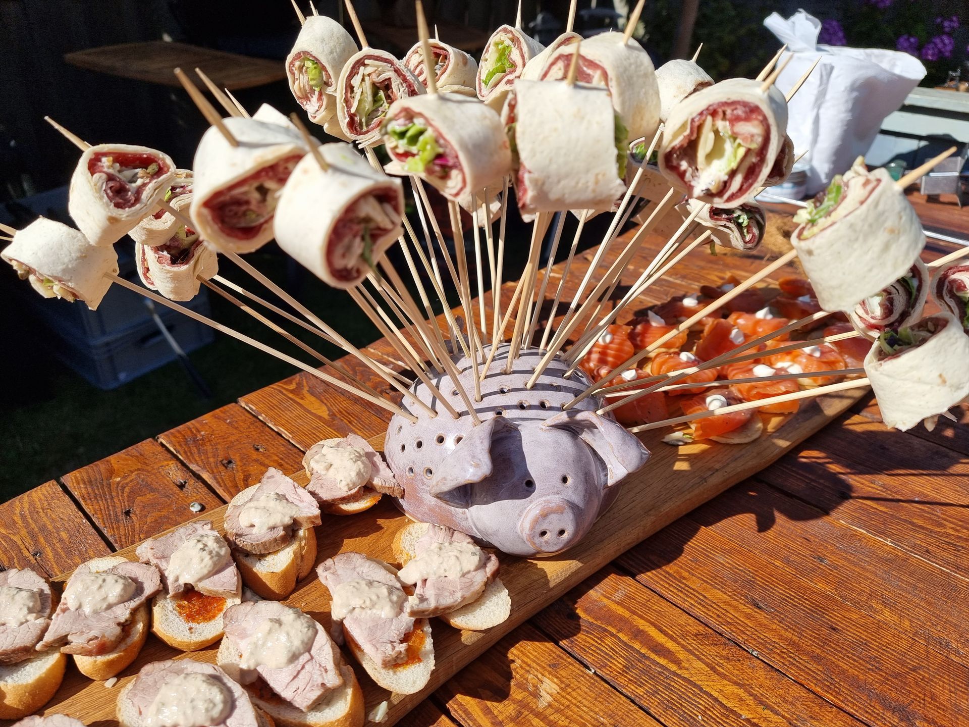 Hapjes uitgestald op een houten plank. Tortillabroodjes aan spiesjes en toastjes met diverse belegsoorten staan ​​uitgestald.