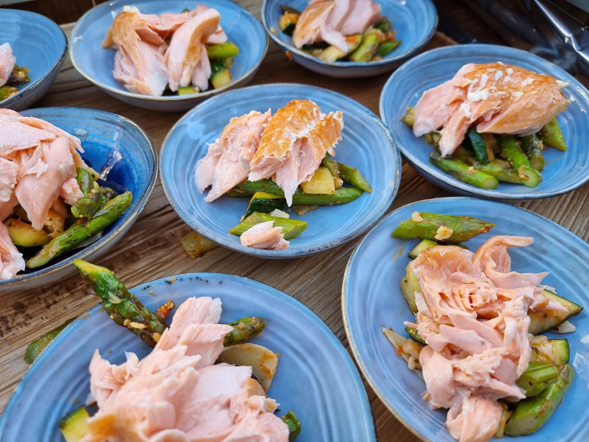 Borden met warm gerookte zalm, asperges  op een houten tafel.