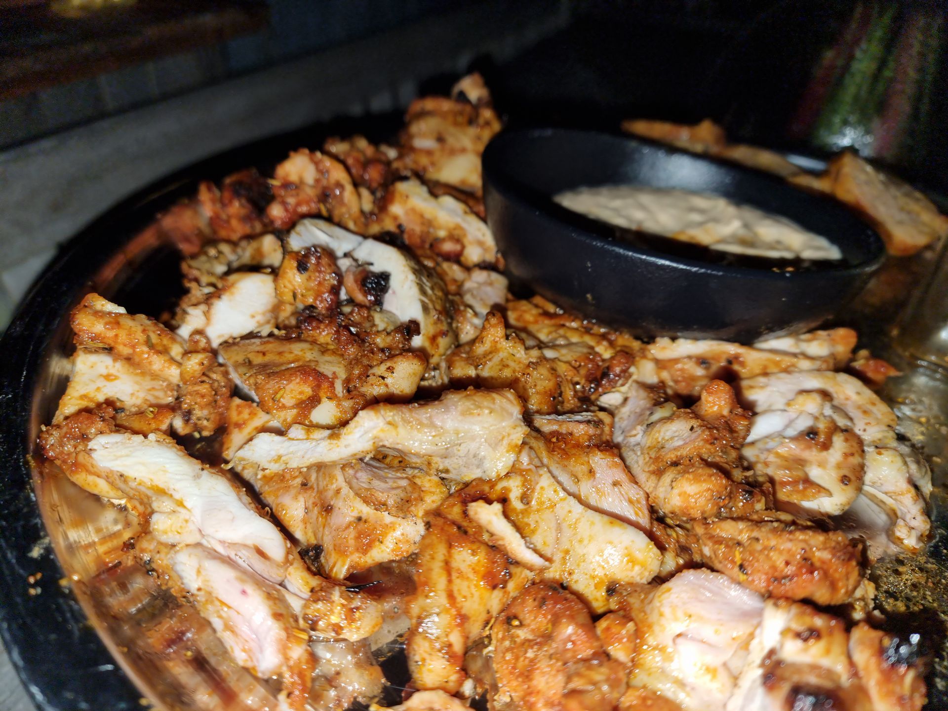 Gegrilde kipstukjes met dipsaus op een schaal.