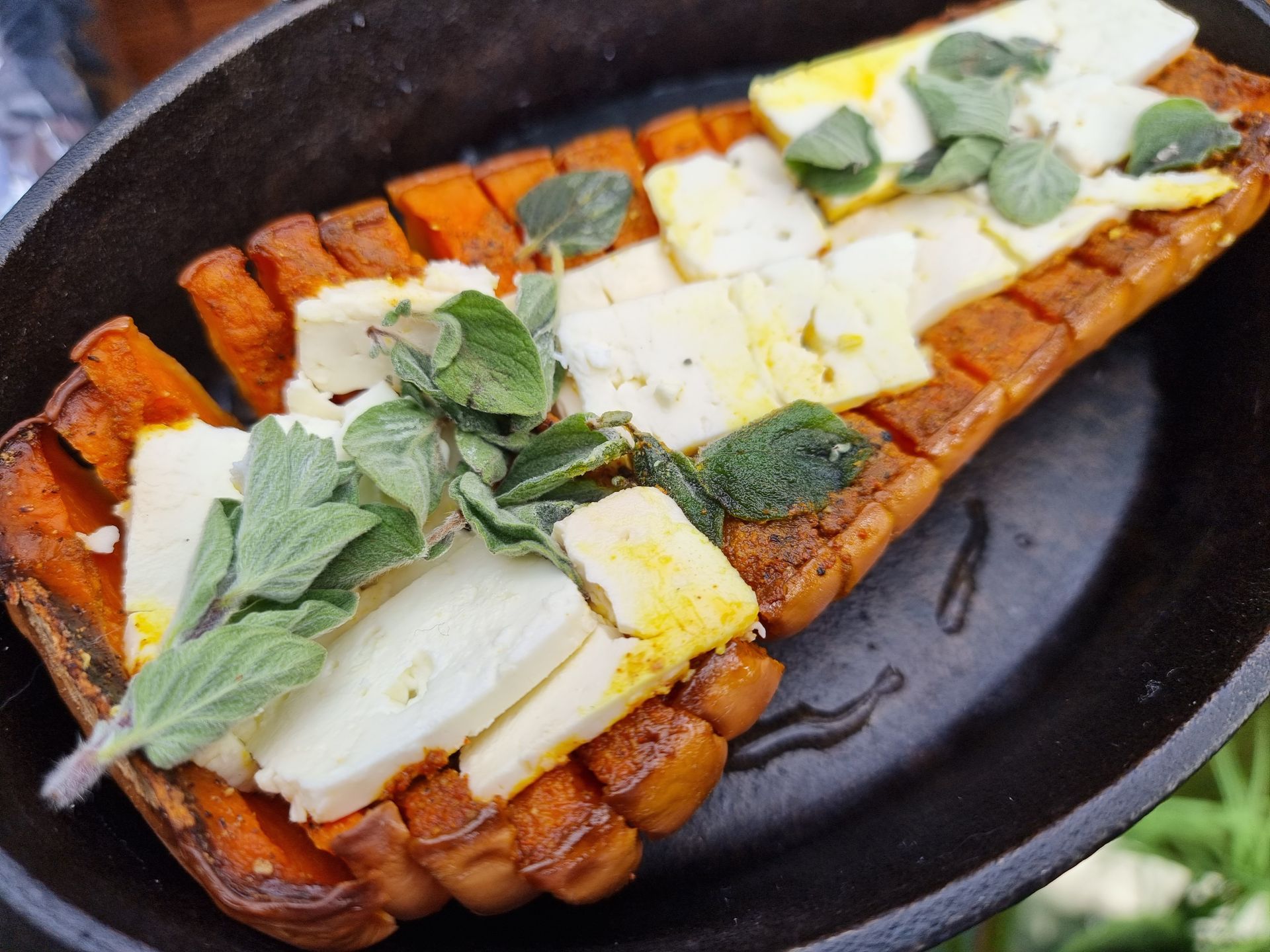 Geroosterde flespompoen met feta en kruiden, geserveerd in een gietijzeren schaal.