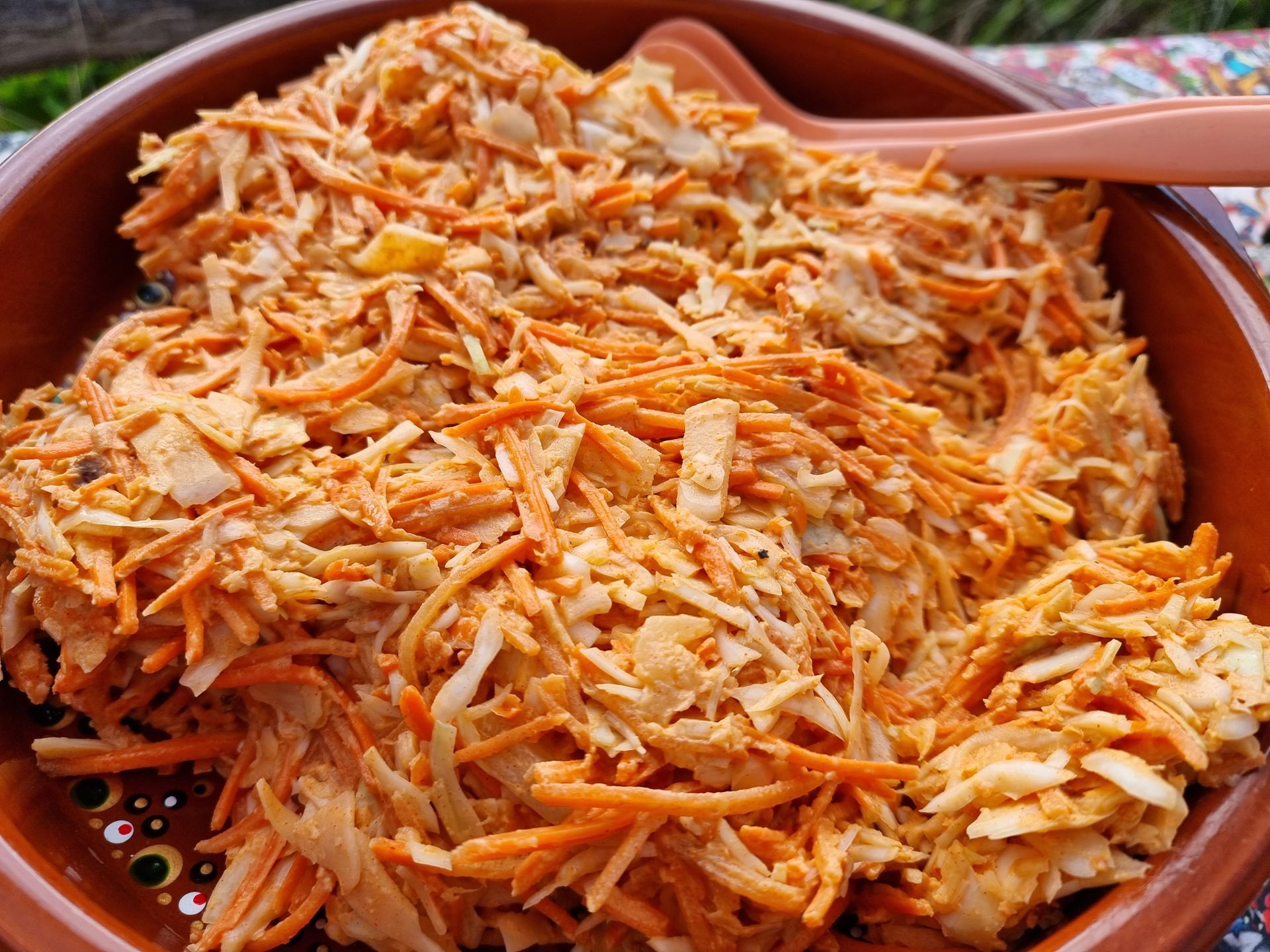 Salade van wortel en witte kool in een bruine kom, gemengd met een romige dressing.