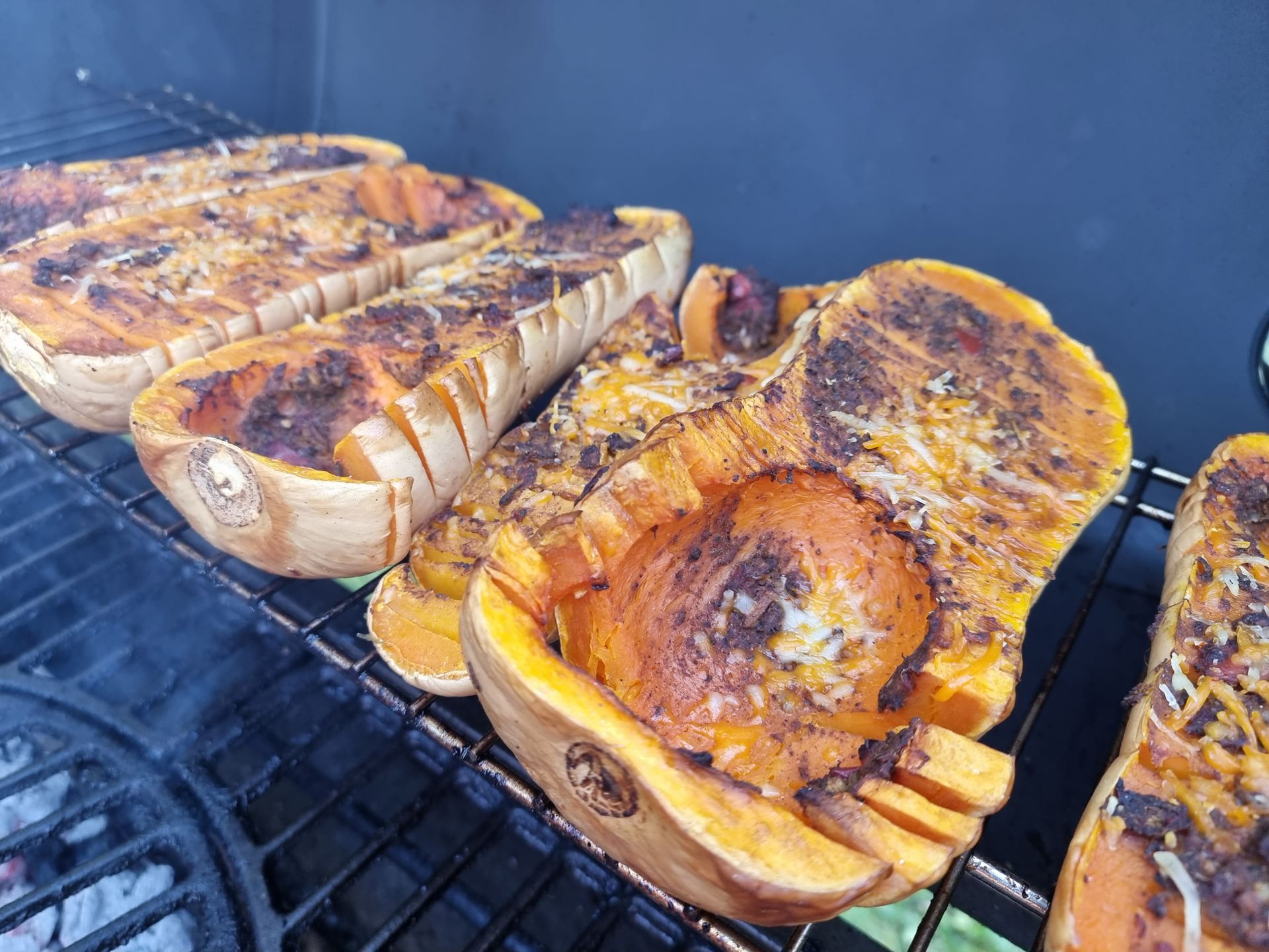 Gegrilde flespompoen op de barbecue. Oranje vruchtvlees met grillstrepen, op een metalen rooster.