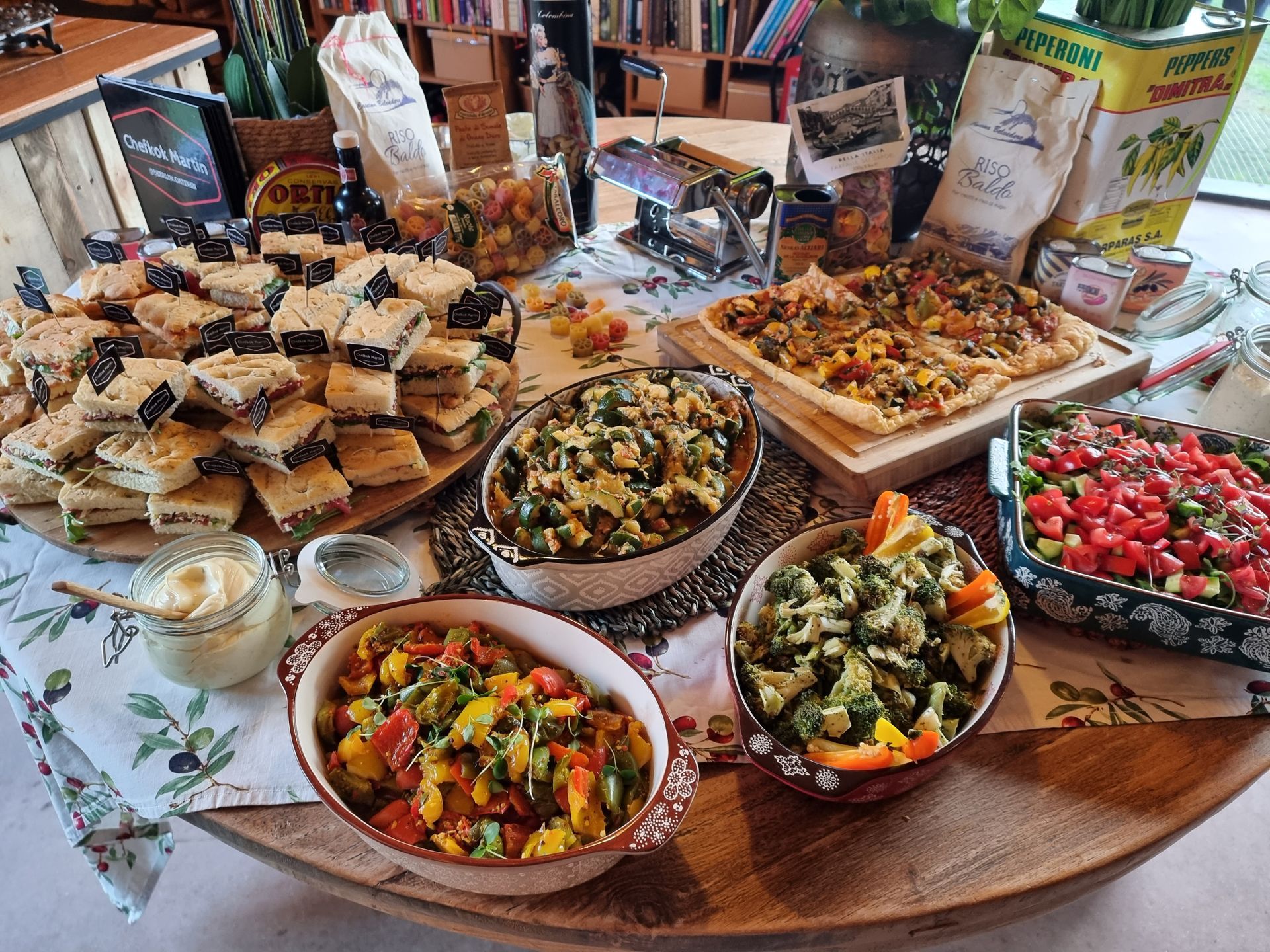 Een tafel vol diverse Italiaanse gerechten, waaronder brood, dipsauzen, salades, flatbread en pasta.